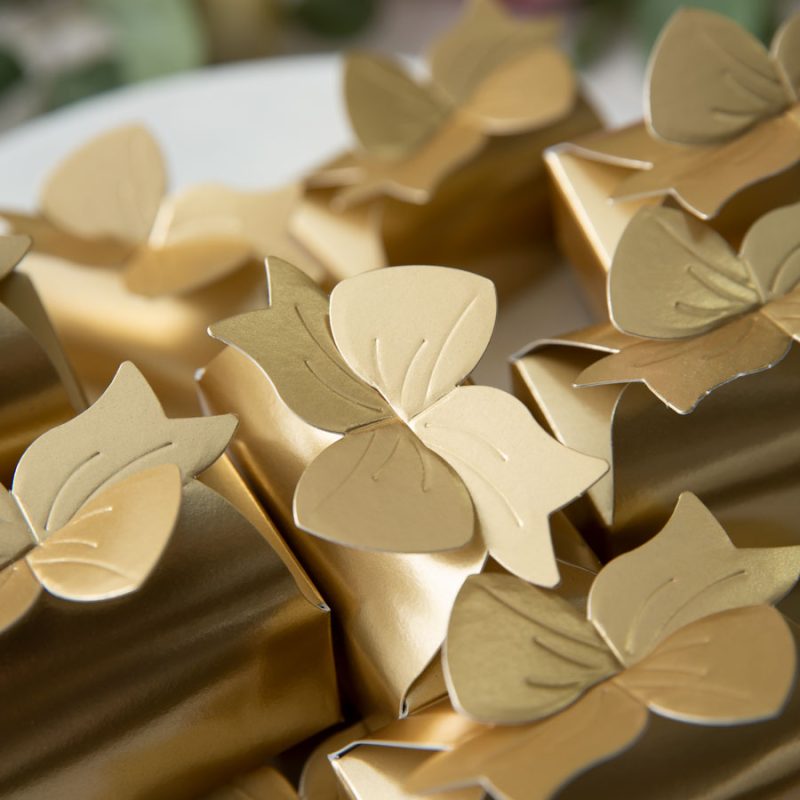 Close-up of gold wedding favor boxes topped with delicate metallic butterfly details.