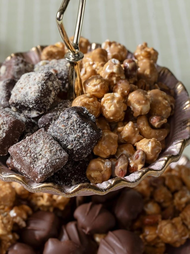 Tiered silver serving dish filled with chocolate toffee and candied popcorn.